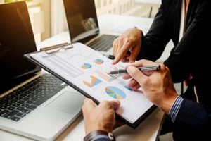 Designed by mindandi / Freepik - image of two people looking at a document with charts on a clipboard